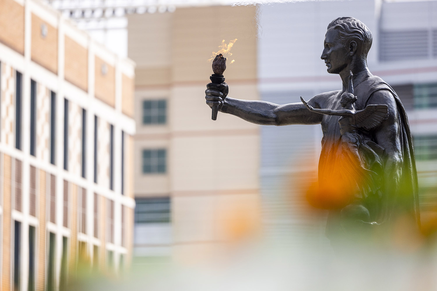 Torchbearer statue with orange marigold flowers in the foreground.