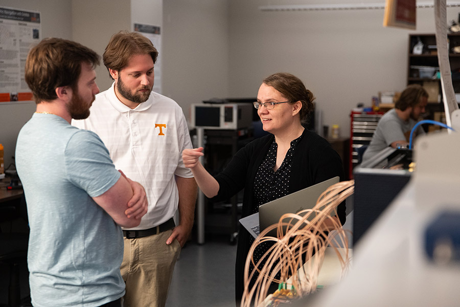 Assistant Professor Catherine Schuman speaks to graduate students in a neuromorphic computing lab in the Min H. Kao Electrical Engineering and Computer Science Building at the University of Tennessee.
