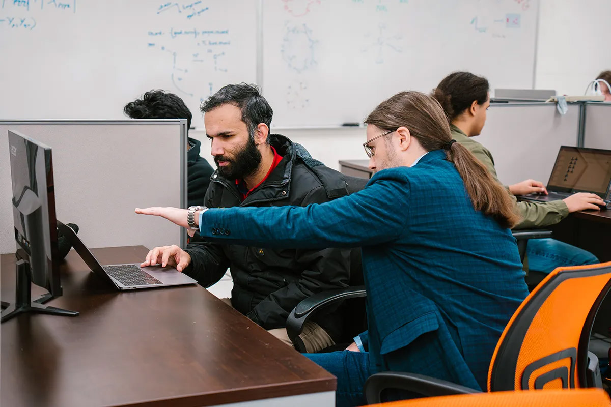 UT Associate Professor Konstantinos Vogiatzis assists a student at a computer.