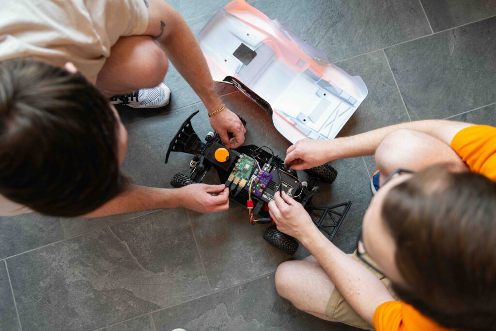 Viewed from above, graduate students Bryson Gullett and Charles Rizzo prepare a small autonomous car for testing on a temporary track in the Zeanah Engineering Complex