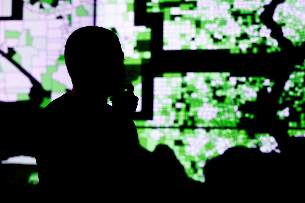 A student in shadow looks at a map showing energy needs across the US in CURENT's Visualization Lab.