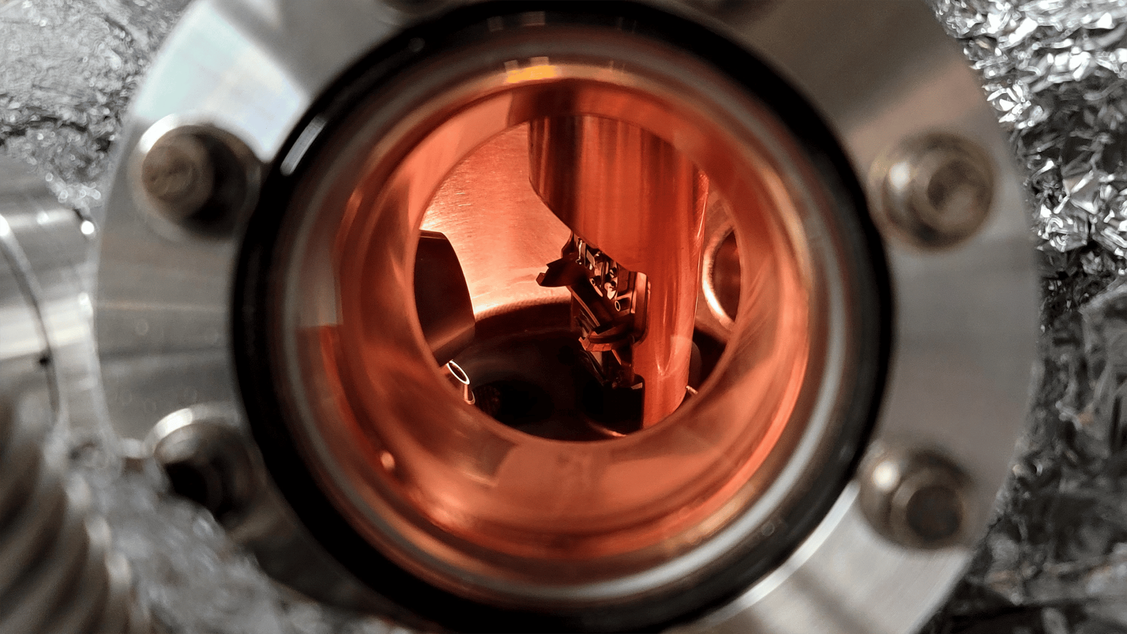 Close up of a round window surrounded in stainless steel that is part of equipment in the Advanced Photoelectron Spectrometer facility.