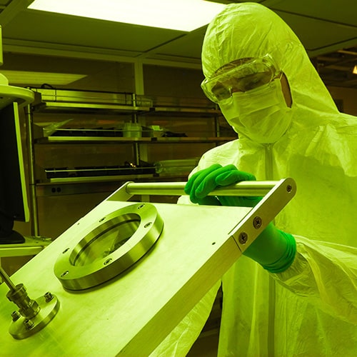 A student wearing protective clothing works in the clean room at IAMM.