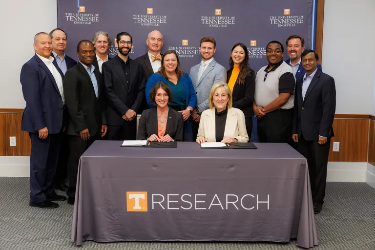 A group of people from UT and Lockheed Martin pose behind a table after the signing of a new master research agreement.