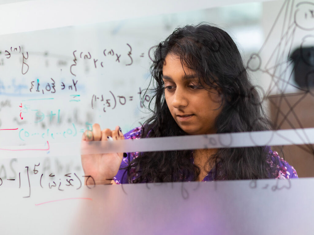 A student works a formula on a window in the IAMM building at the University of Tennessee