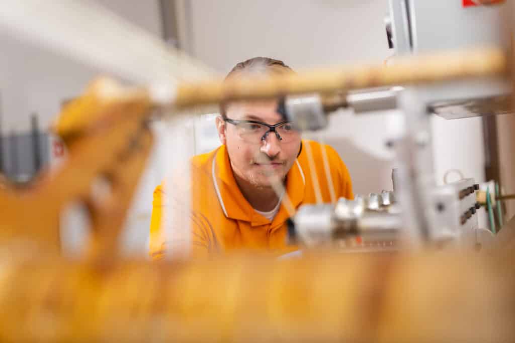William Henken, a Volkswagen Doctoral Fellow, runs an automated filament winder manufacturing glass fiber reinforced polymeric (GFRP) composites inside an IAMM lab on December 07, 2022.