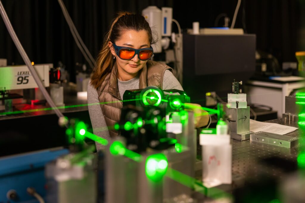 Woman wearing protective eyeglasses operates the Brillouin scattering spectroscopy with a green laser in the Light Scattering Laboratory at IAMM.