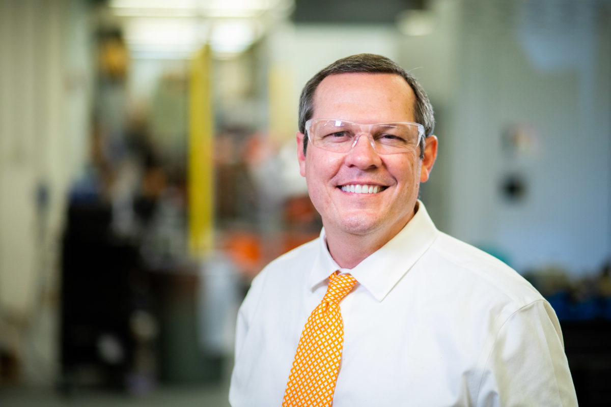 Tony Schmitz wears an orange tie and smiles.