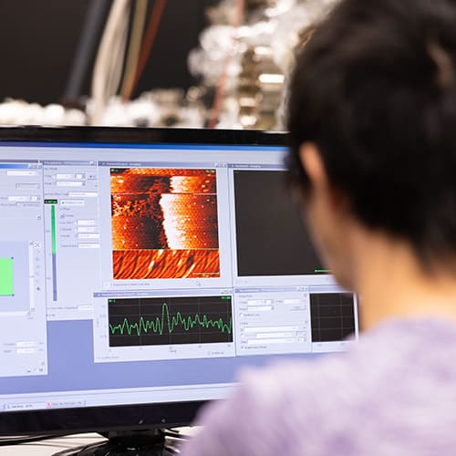 A person looks at a monitor as the molecular beam epitaxy is in operation.