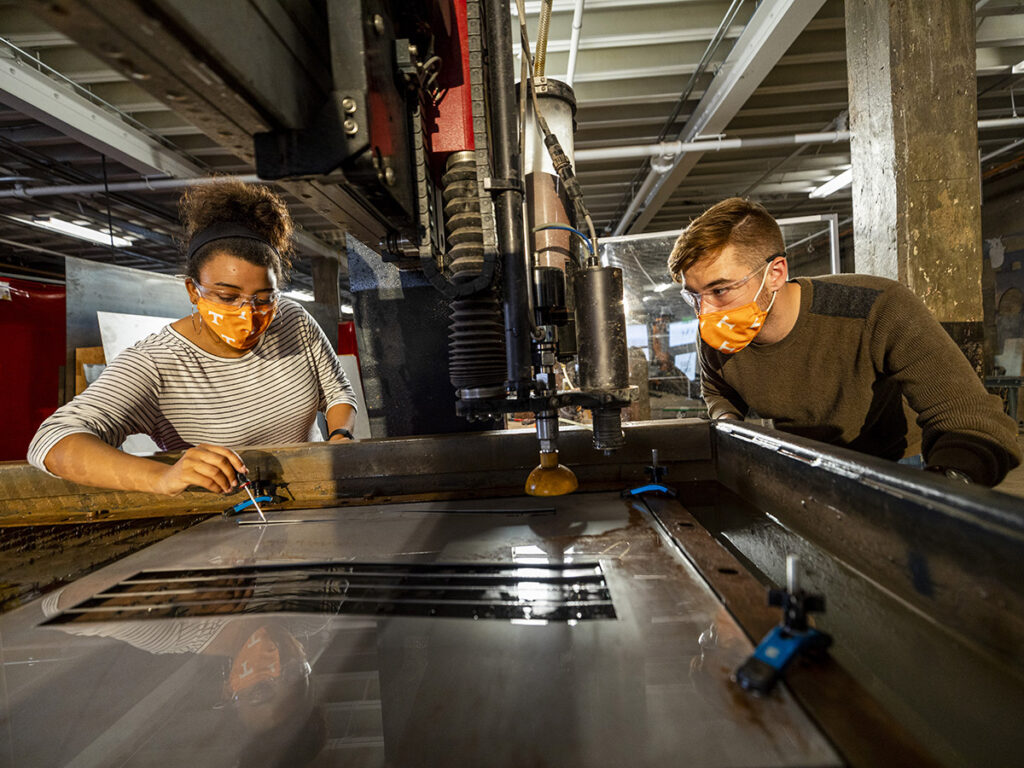Students remove pieces of cut metal from an abrasive waterjet cutter inside the UT Fab Lab at the University of Tennessee.
