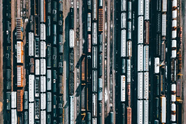 Birds-eye view of numerous railway lines, many with trains composed of multiple cars.