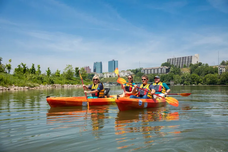 Chancellor Donde Plowman and several other people in orange kayaks on the Tennessee River.