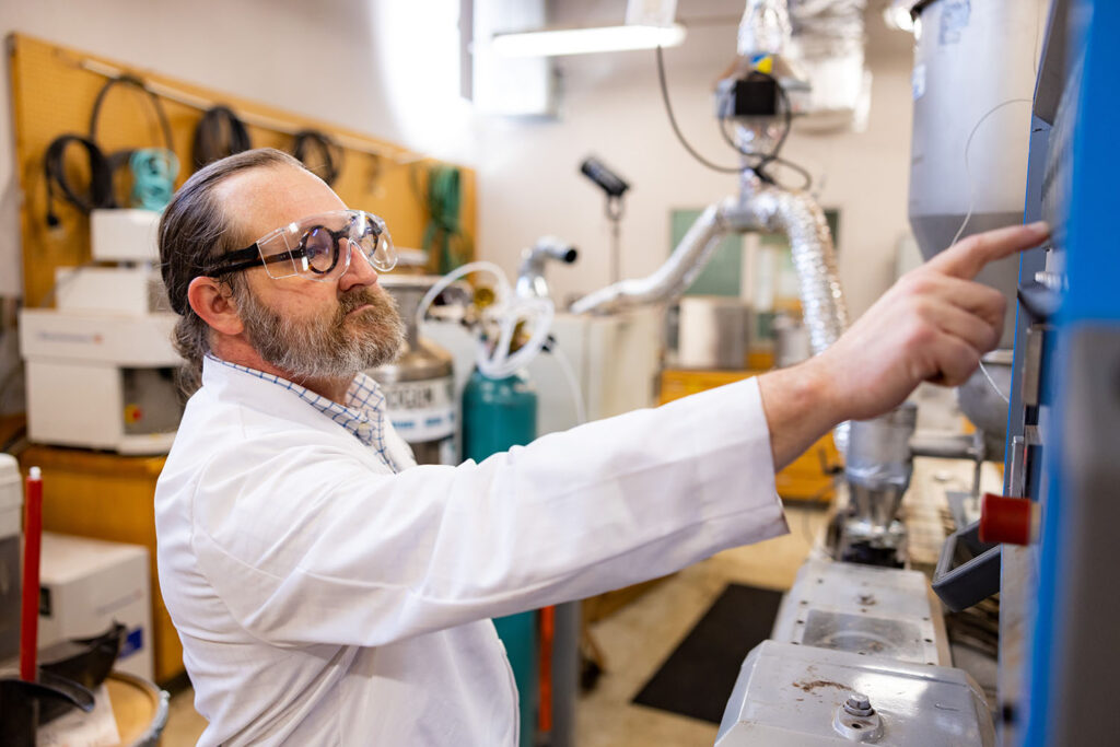 David Harper wears safety goggles and operates equipment in a lab at the Center for Renewable Carbon.