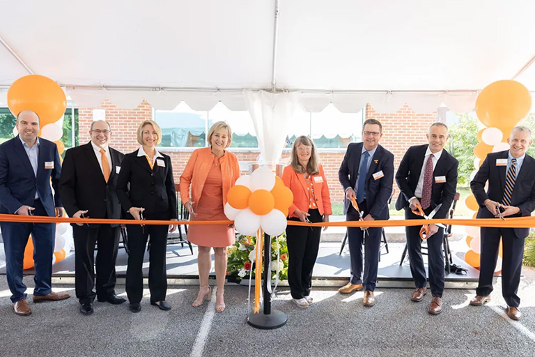 Group of leaders from UT and Eastman prepare to cut an orange ribbon.