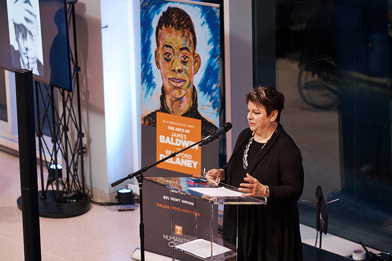 Humanities Center director Amy Elias stands behind a podium speaking at an event.