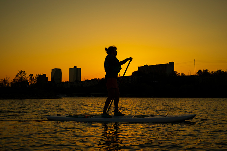 A paddleboarder in the Tennessee River at sunset.