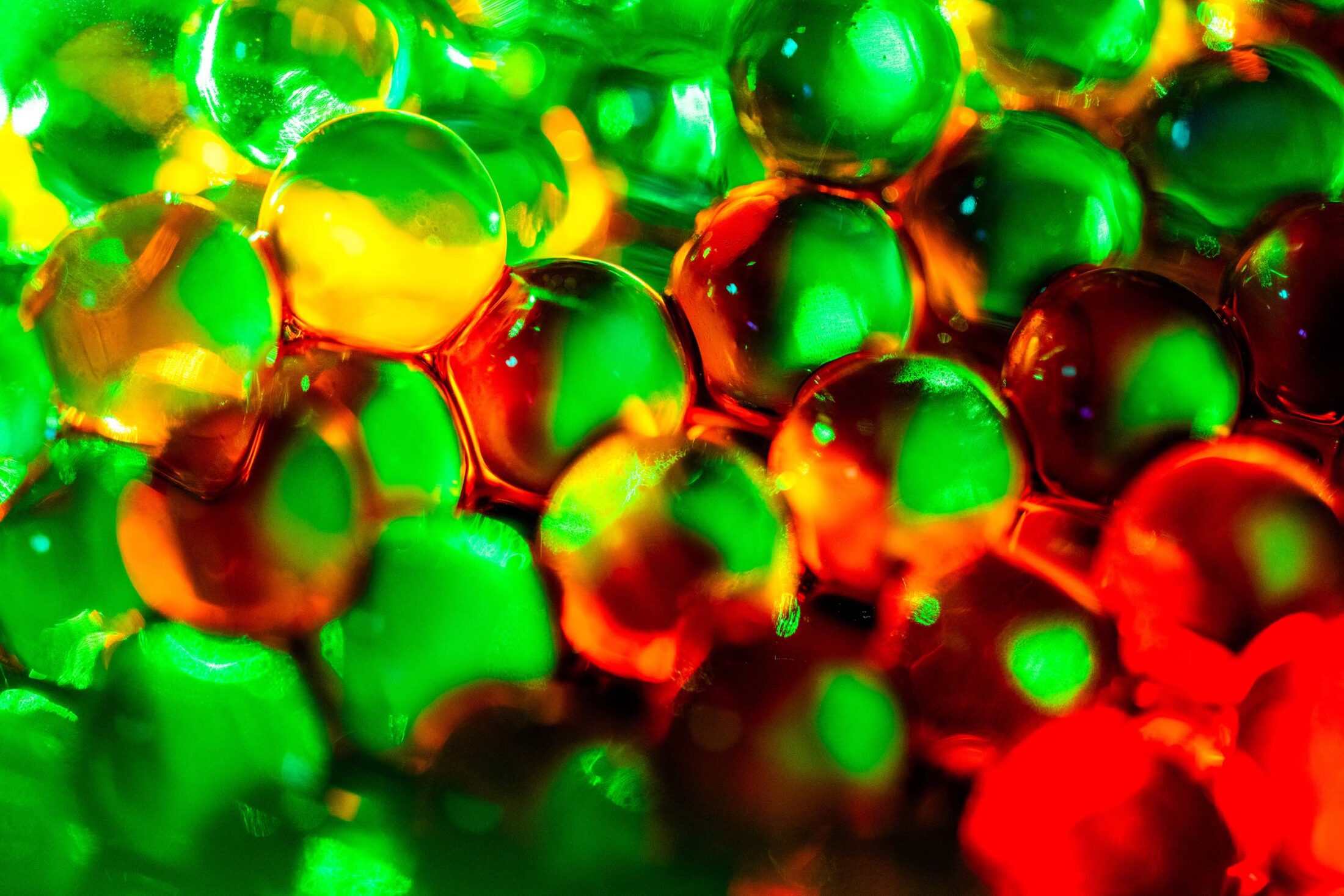 Close up of red dye dispersing in a jar of clear beads.