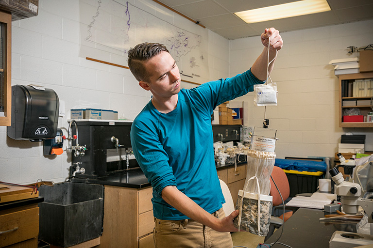 A researcher holds up a device used in mosquito research.