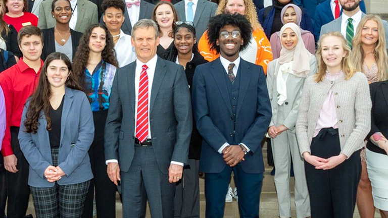 Group of students including Caleb Napper stand beside the Tennessee governor outside a building.