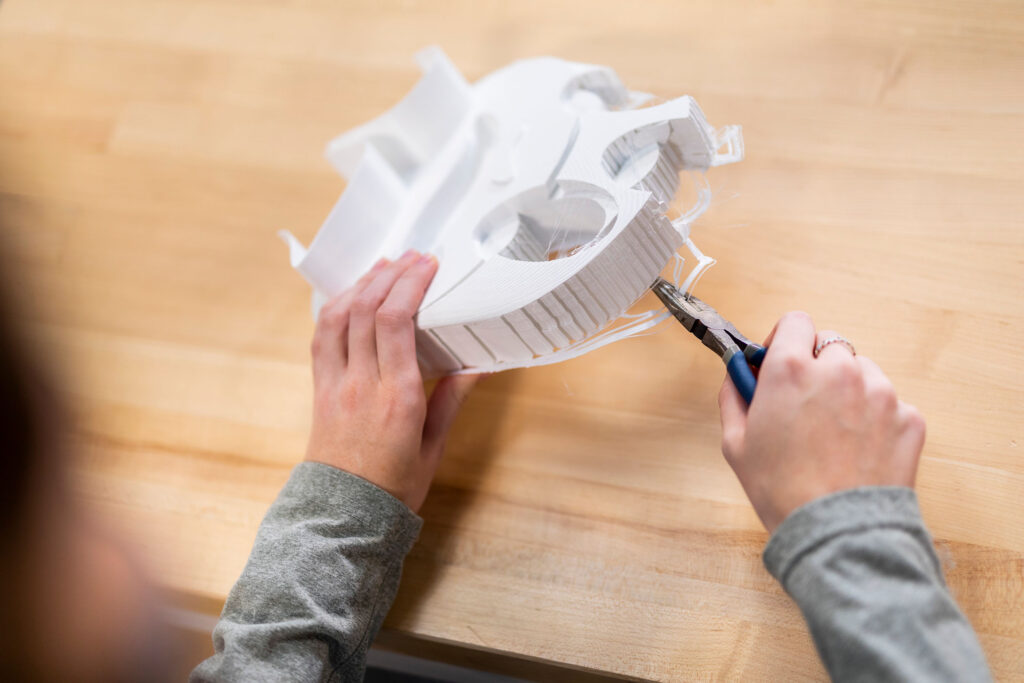 In the Fab Lab, a student pulls off extra material from a 3D-printed model.