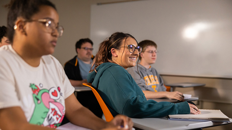 Several students sit at desks in a classroom.