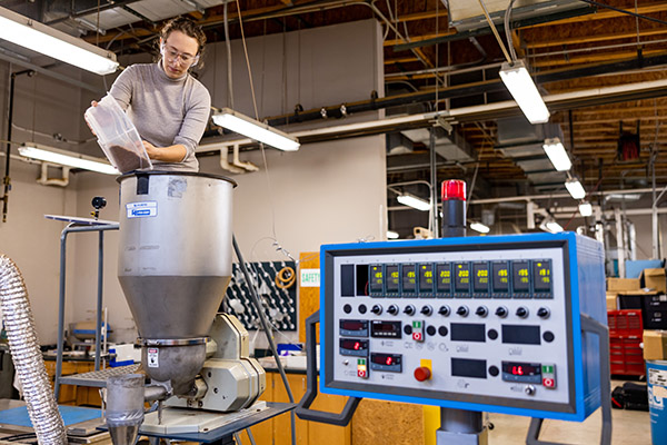 Cecile Grubb feed pellets and natural fibers into an extruder inside a Center for Renewable Carbon (CRC) lab at the UT Agriculture campus.