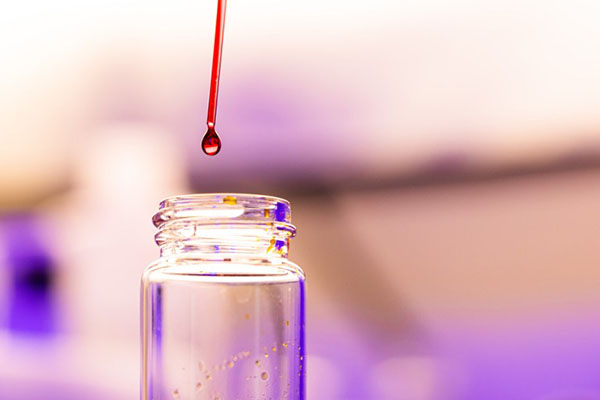 A solution droplet hangs on the end of a dropper above a glass vial in the Polymer Characterization Laboratory.