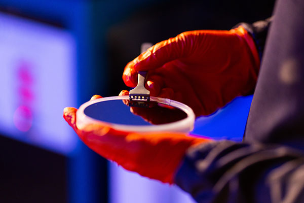 A person holding a thin film synthesis in the sputtering lab at UT.