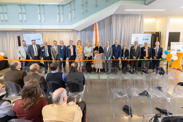 Several people including UT Chancellor Donde Plowman and Joelle Phillips, president of AT&T Tennessee, prepare to cut an orange ribbon.