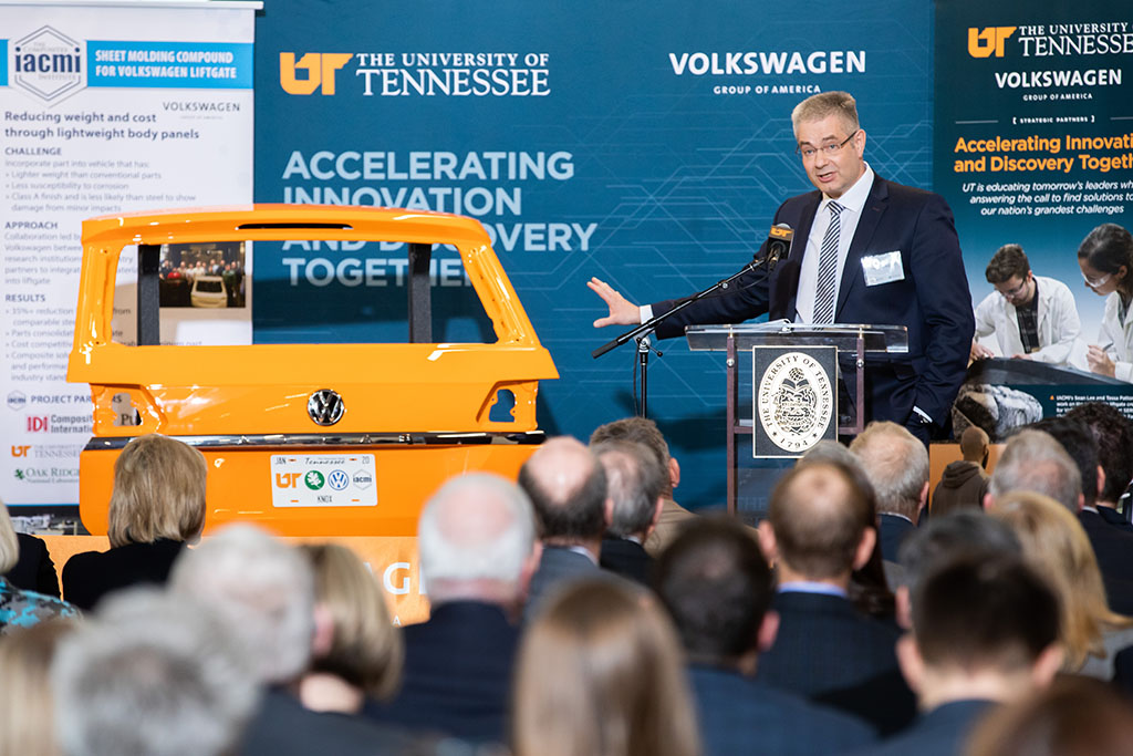 Nikolai Ardey, executive director of Volkswagen Group Innovation, speaks during an announcement ceremony with a UT orange Volkswagen liftgate beside him.