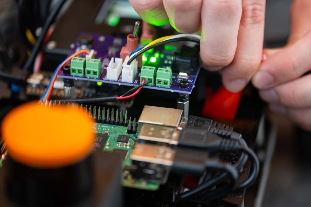 Close up of hand making adjustment to the circuitry in an autonomous RC car.