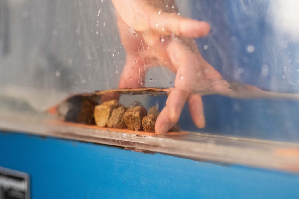 Close view of a hand placing an obstacle in a flume with moving water.