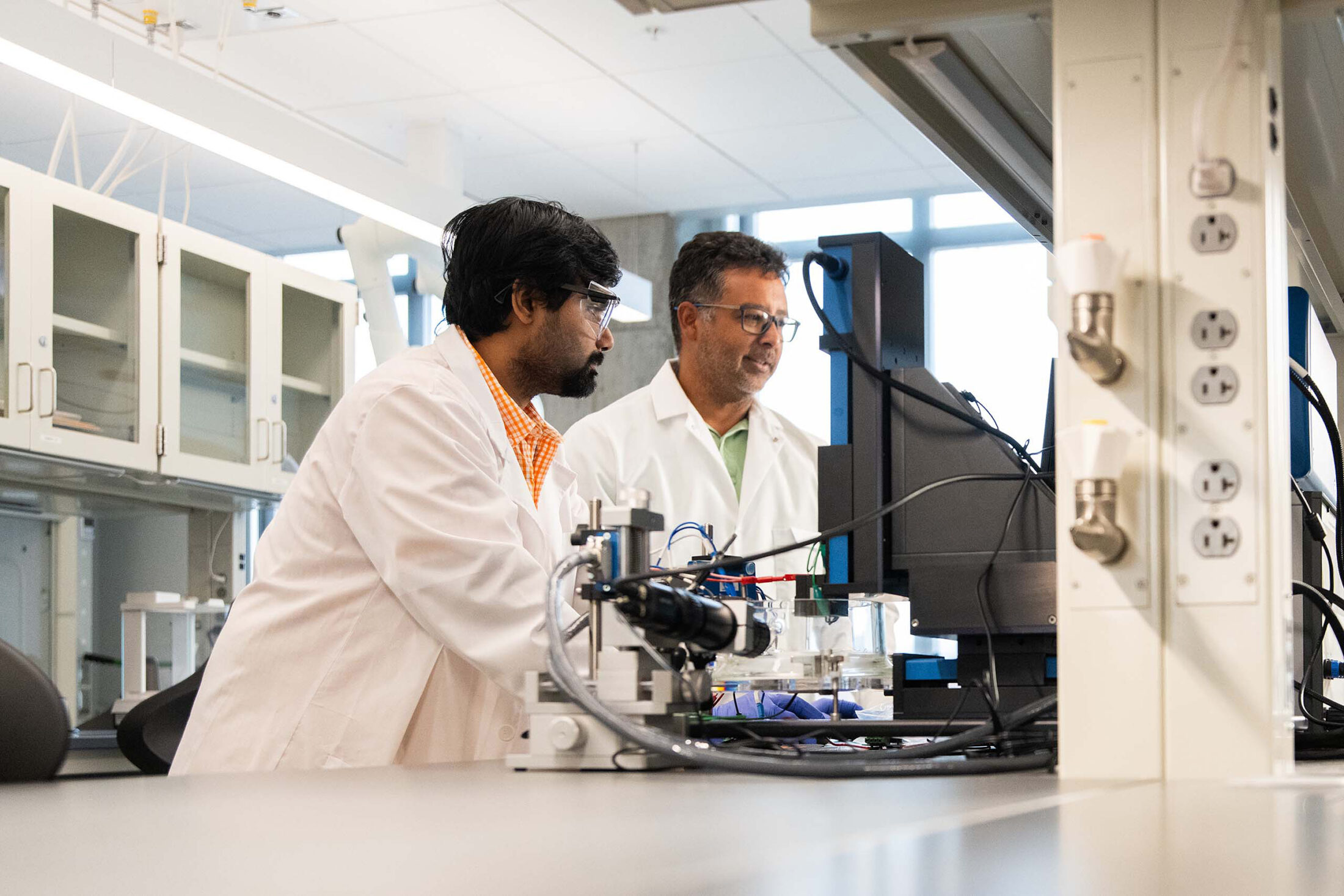 Anirban Roy and Gabriel Goenaga-Jiménez operate a scanning electrochemical workstation in a lab in Zeanah Engineering Complex.