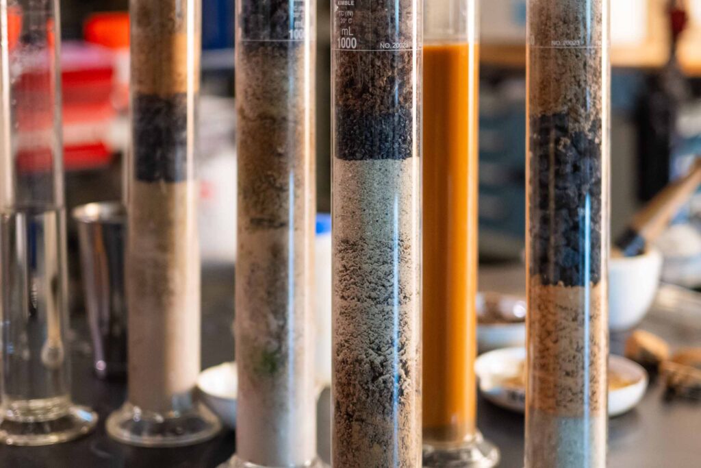 Several tubes with stacked soil samples on a lab table.