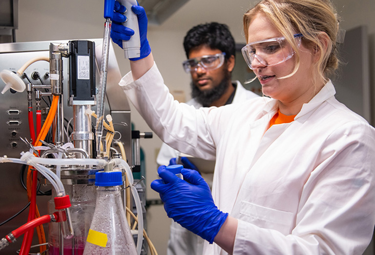 PhD student Carrie Sanford conducts an experiment in the bioreactor room in Senter Hall as Galib Hassan Khan, also a graduate student, observes.