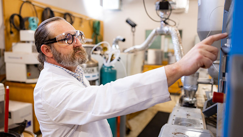 David Harper adjusts the settings on an extruder machine inside a Center for Renewable Carbon (CRC) lab at the UTK Agriculture campus.