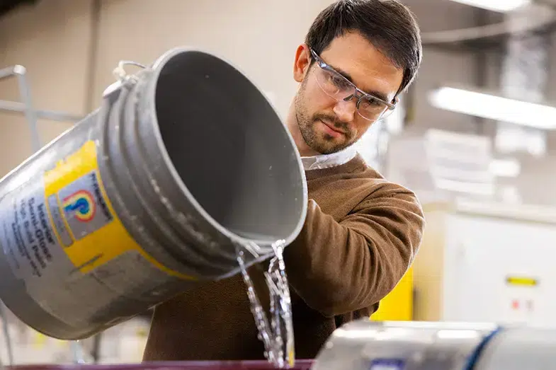 A researcher pours liquid into a piece of equipment in a lab at the University of Tennessee, Knoxville.