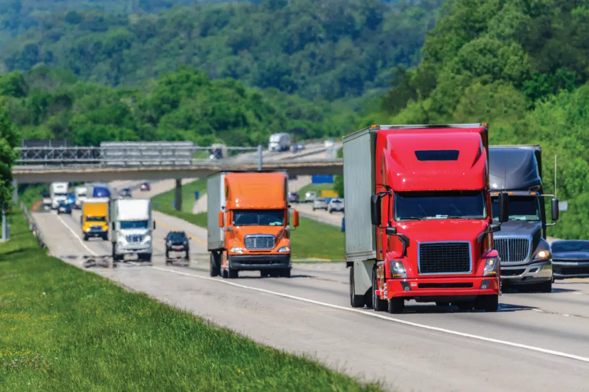 Tractor trailer trucks travel down an interstate highway.