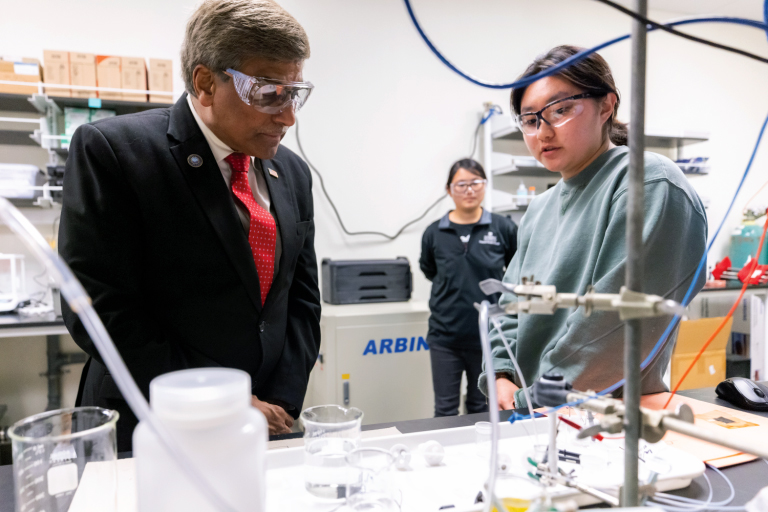 NSF Director Sethuraman Panchanathan listens as a woman explains her research at the UT Research Park at Cherokee Farm.