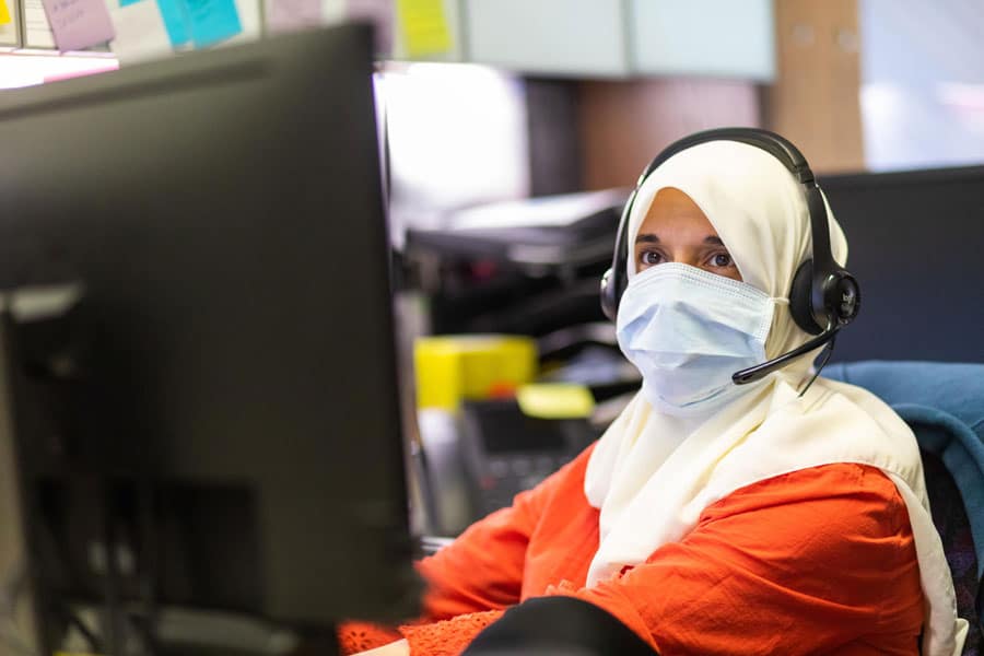 A faculty member works in their office during a setup photoshoot while wearing a mask and social distancing at Strong Hall. July 10, 2020.