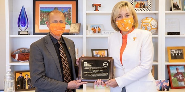 Tim Cross, senior vice chancellor and senior vice president for agriculture, and Chancellor Donde Plowman with a plaque from the Association of Public Land-Grant Universities.