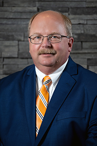 David Anderson wearing a blue jacket and orange striped tie.
