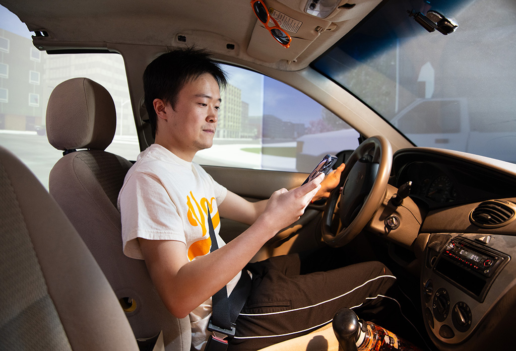 Hairuilong Zhang uses his cell phone while driving in the Driving Simulator Lab.