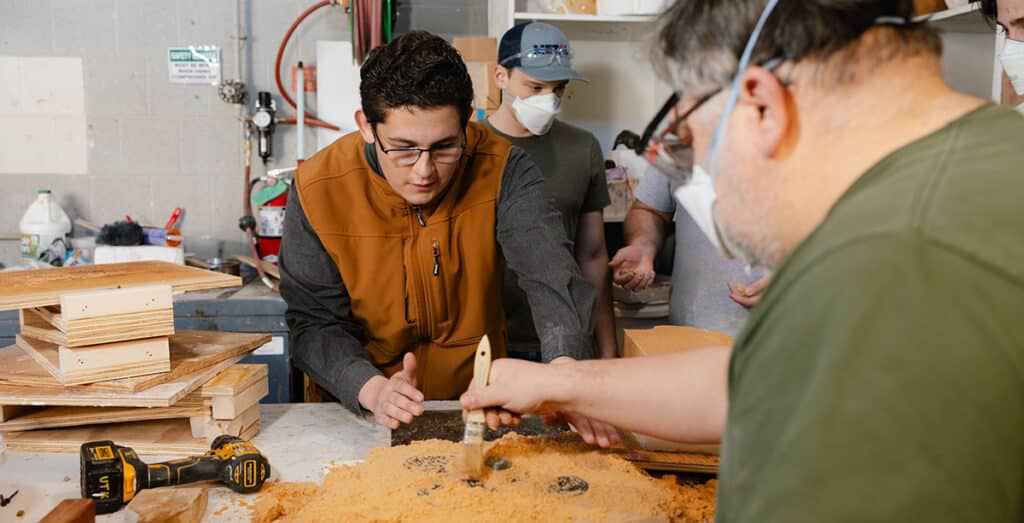 Three participants make sand molds as part of the metal casting portion of METAL Bootcamp at the University of Tennessee, Knoxville's foundry in the Art and Architecture Building.