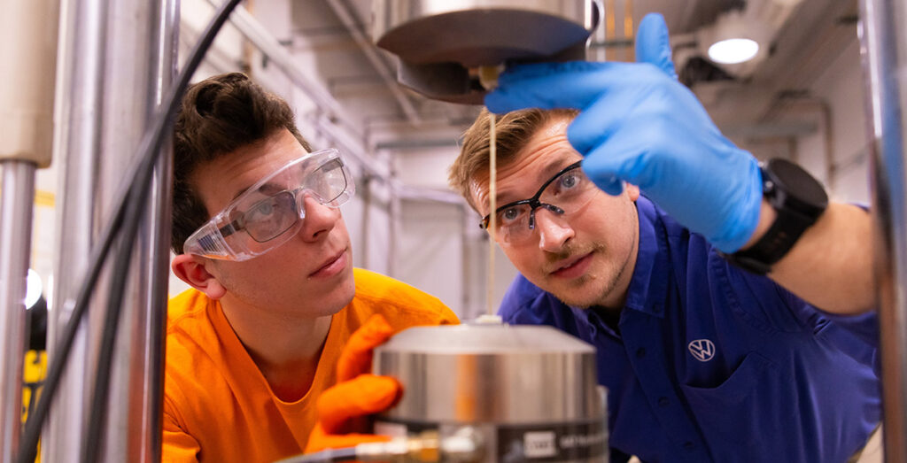 William Henken, a Volkswagen Doctoral Fellow, talks with a student about tensile testing of glass fiber reinforced polymeric (GFRP) composites in a lab inside the Science & Engineering Building at the University of Tennessee.