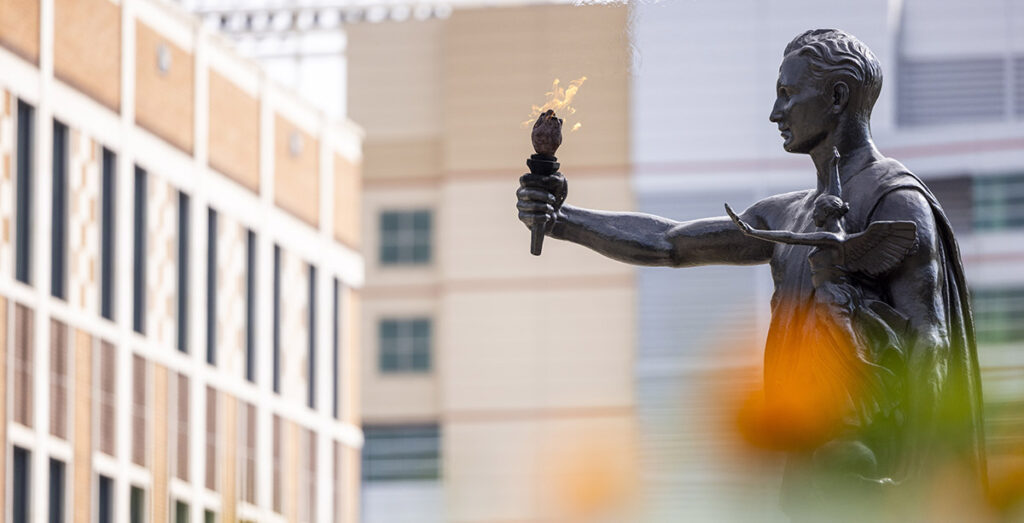 Torchbearer statue with orange marigold flowers in the foreground.