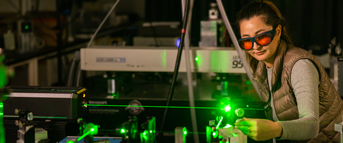 A woman operates the Brillouin scattering spectroscopy with a green laser in the Light Scattering Laboratory.