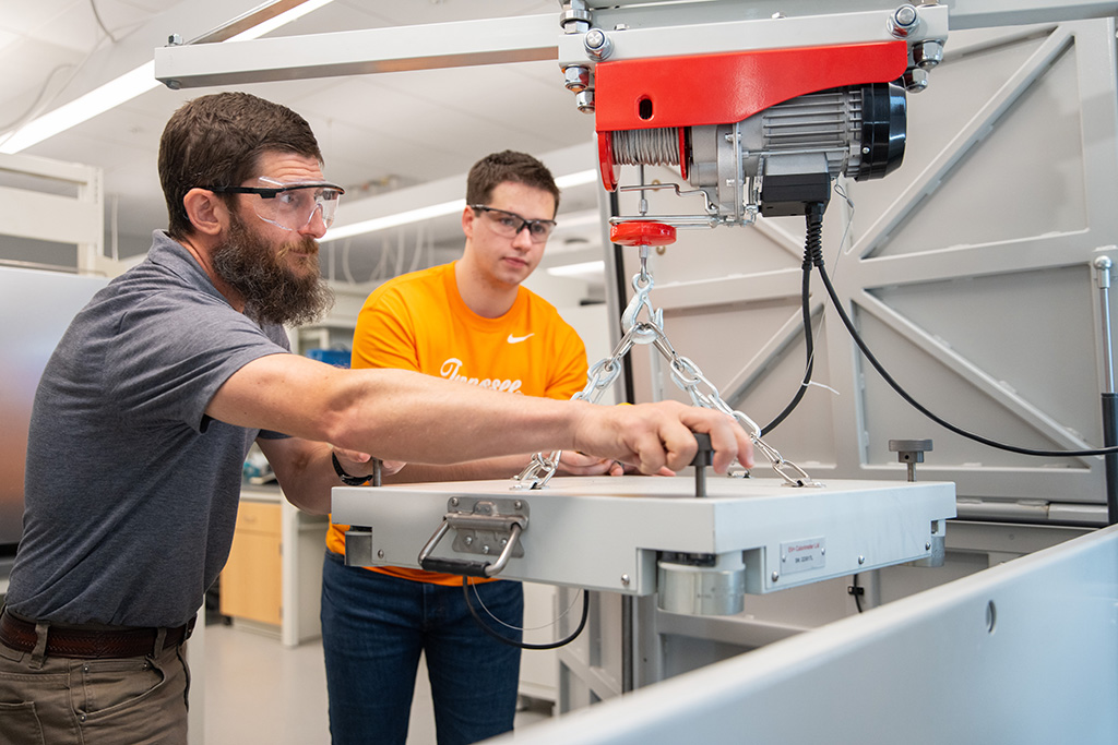 Doug Aaron and Preston Young move the heavy lid of the Accelerating Rate Calorimeter with the help of a crane.