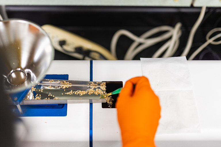Close look at orange gloves sorting biomass samples into a particle-sized 3D image analyzer.