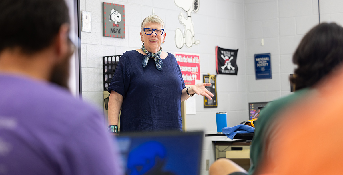 Laurie Meschke speaks in front of a group of teachers in a high school classroom.